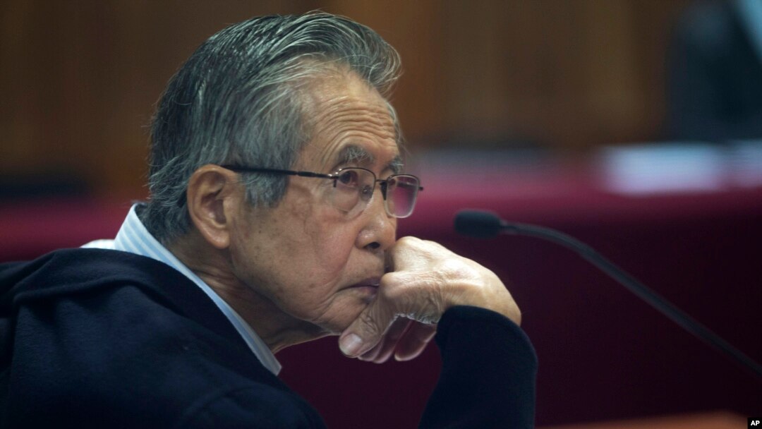 ARCHIVO - El expresidente peruano Alberto Fujimori, encarcelado, fotografiado a través de una ventana de vidrio, asiste a su juicio en una base policial en las afueras de Lima, Perú, el 28 de junio de 2016.