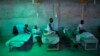The daughter of 84-year-old Armant Germain replaces the sheets on her bed, in the cholera ward at a hospital in Les Cayes Haiti, Oct. 11, 2016. 