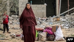Uma mulher ao lado de objectos recuperados de edifício atingido durante a noite por bombardeamentos israelitas em Rafah, no sul da Faixa de Gaza, a 26 de março de 2024, no meio do conflito em curso no território palestiniano entre Israel e o grupo militante