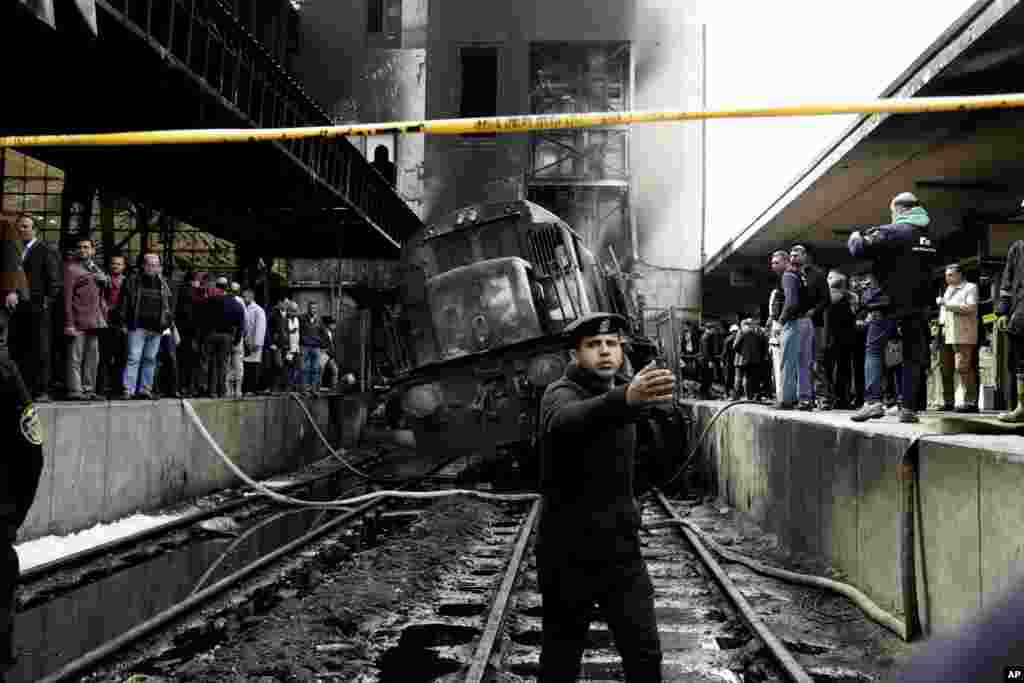 Policemen stand guard in front of a damaged train inside Ramsis train station in Cairo, Egypt. A medical official said at least 20 people have been killed and dozens injured after a railcar rammed into a barrier inside the station, which caused an explosion of the fuel tank and triggered a huge blaze that engulfed that part of the station.