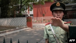A paramilitary police officer gestures outside the Belgium embassy in Beijing, June 19, 2019. A Belgian diplomat was to travel to China's Xinjiang region June 18 to confirm the whereabouts of a Uighur family escorted from Belgium's embassy in Beijing by police last month.