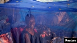 FILE - A woman sits inside a mosquito tent in the town of Abyei, Sudan. 