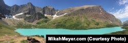 With its stunning turquoise waters, Cracker Lake stands out like a jewel against a backdrop of greens and grays.