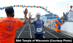 A man completes the Sikh Temple of Wisconsin's 6k "Chardhi Kala" Run with a high five.