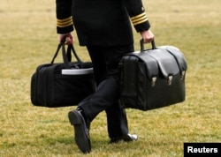 FILE - A military aide, carrying the "football" containing launch codes for nuclear weapons, accompanies U.S. President Donald Trump onto Marine One upon Trump's departure from the White House in Washington, Feb. 3, 2017.