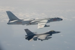 FILE - A Taiwanese F-16 fighter jet flies next to a Chinese H-6 bomber, top, in Taiwan's air defense zone, in this handout photo taken and released Feb. 10, 2020, by Taiwan's Defense Ministry.