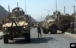 FILE - A US soldier directs his colleagues at the site a bomb attack that targeted several armored vehicles belonging to forces attached to the NATO Resolute Support Mission, in downtown of Kabul.
