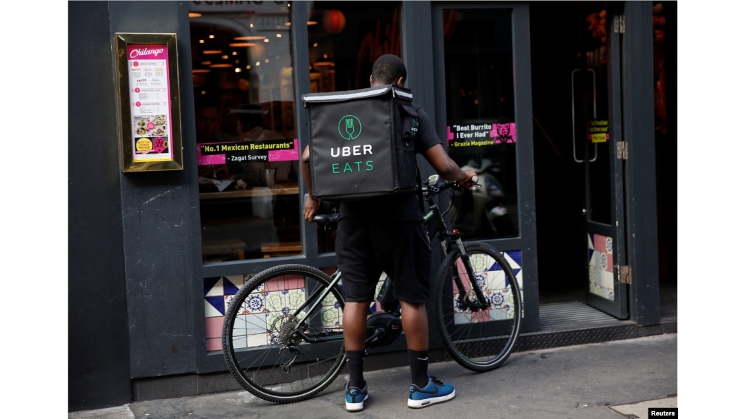 An UberEATS food delivery courier prepares his bike in London on September 7, 2016. Uber is advertising to fill jobs from general managers to bike couriers.