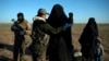 FILE - A woman is frisked by a U.S.-backed Syrian Democratic Forces (SDF) fighter at a screening area after being evacuated out of territory held by Islamic State group militants, in the desert outside Baghuz, Syria, March 1, 2019.