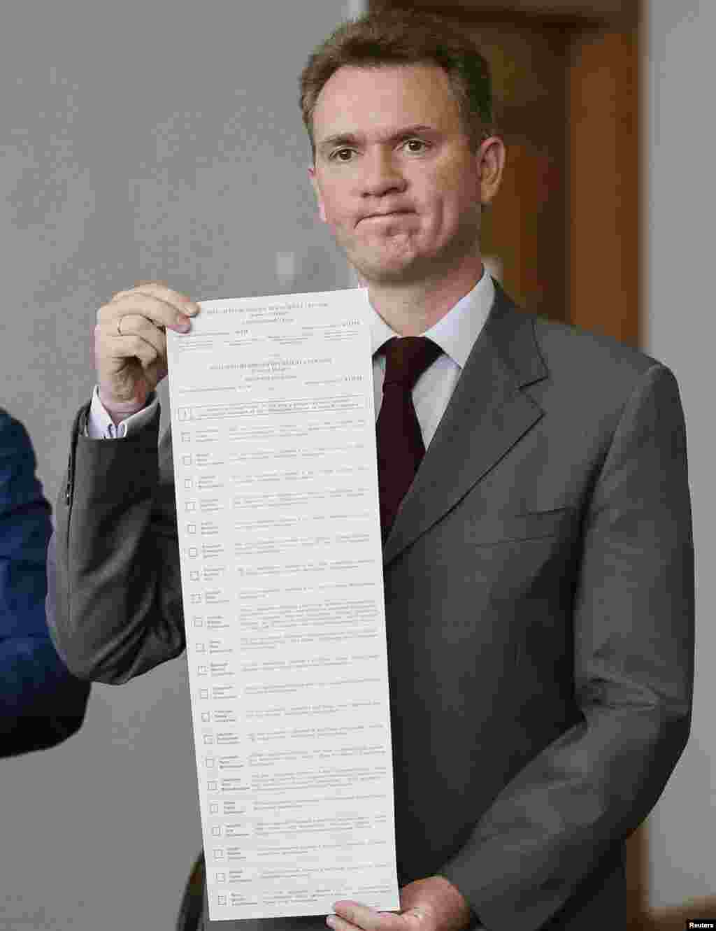 Mykhaylo Okhendovsky, head of Ukraine's Central Election Commission, shows a long ballot with names of 21 presidential candidates, at a news conference, in Kyiv, May 14, 2014.