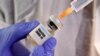 A woman holds a small bottle labbeled with a "Vaccine COVID-19" sticker and a medical syringe in this illustration taken April 10, 2020.