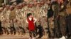 A girl stands in front of fighters from the Syrian Democratic Forces at the funeral of a fellow fighter killed in Hajin during battles against the Islamic State group, in the Kurdish-controlled city of Qamishly in northeastern Syria, Dec. 3, 2018. 