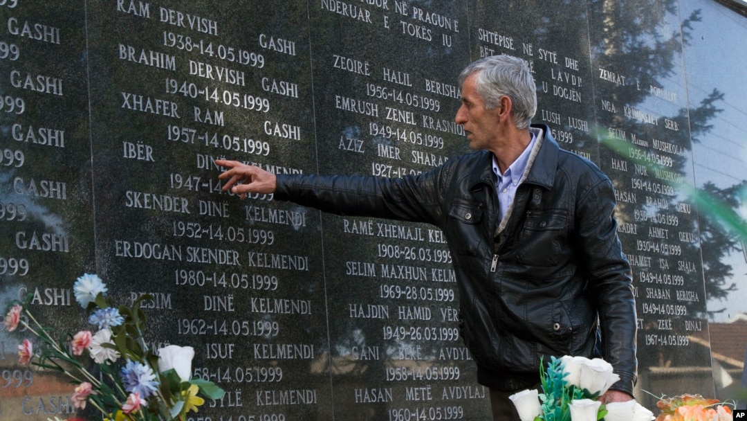 FILE - A survivor of the Cuska massacre points out the names of family members as he visits a cemetery in the village of Cuska, Kosovo, on Feb. 11, 2014.