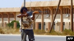 FILE - A fighter loyal to the U.N.-recognized Government of National Accord points his gun toward enemy lines during clashes with forces loyal to strongman Khalifa Haftar, in Espiaa, south of the Libyan capital, Tripoli, Aug. 21, 2019.