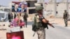 FILE - Members of Russian and Syrian forces stand guard near posters of Syrian President Bashar al-Assad and his Russian counterpart, Vladimir Putin, at the Abu Duhur crossing on the eastern edge of Idlib province, Syria, Aug. 20, 2018.