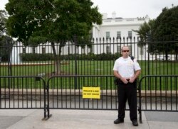 FILE - A member of the United States Secret Service Uniformed Division looks out over Pennsylvania Avenue as he stands in front of a temporary barrier in front of the White House in Washington, Oct. 3, 2014.