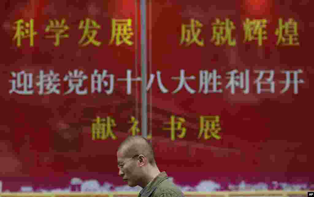 2012年11月8日，中共18大在北京召开。在上海，一位男士走过上海某书店迎接18大官方的宣传招贴。