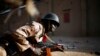 FILE - A Malian soldier takes cover behind a truck during exchanges of fire with jihadists in Gao, northern Mali, Feb. 10, 2013.