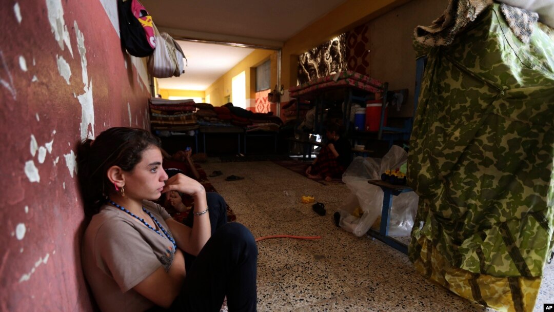 FILE - An internally displaced Yazidi who fled from an Iraqi town after advances by Islamic militants takes shelter at a school in Dahuk, 260 miles (420 kilometers) northwest of Baghdad.