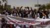 Protesters hold a banner calling for the release of political prisoners, during a march by members of the Sudanese medical profession syndicate, at the sit-in inside the Armed Forces Square, in Khartoum, Sudan, Wednesday, April 17, 2019. 