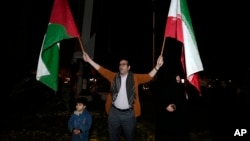 Manifestante agita bandeiras iraniana e palestiniana durante protesto anti-Israel em Teerão, Irão, 14 abril 2024 I