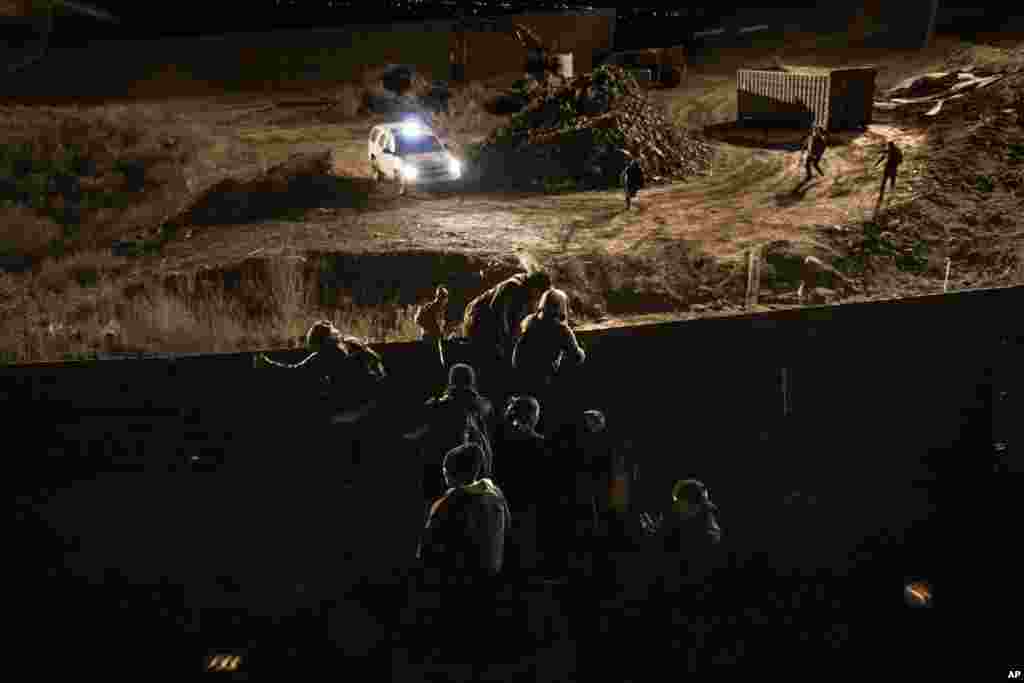 Migrants climb the border fence and jump inside the United States to San Diego, from Tijuana, Mexico, Dec. 25, 2018.