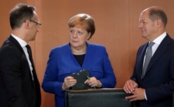 FILE - German Chancellor Angela Merkel, German Foreign Minister Heiko Maas, left, and German Finance Minister Olaf Scholz talk as they arrive for the weekly Cabinet meeting at the chancellery in Berlin, May 15, 2019.