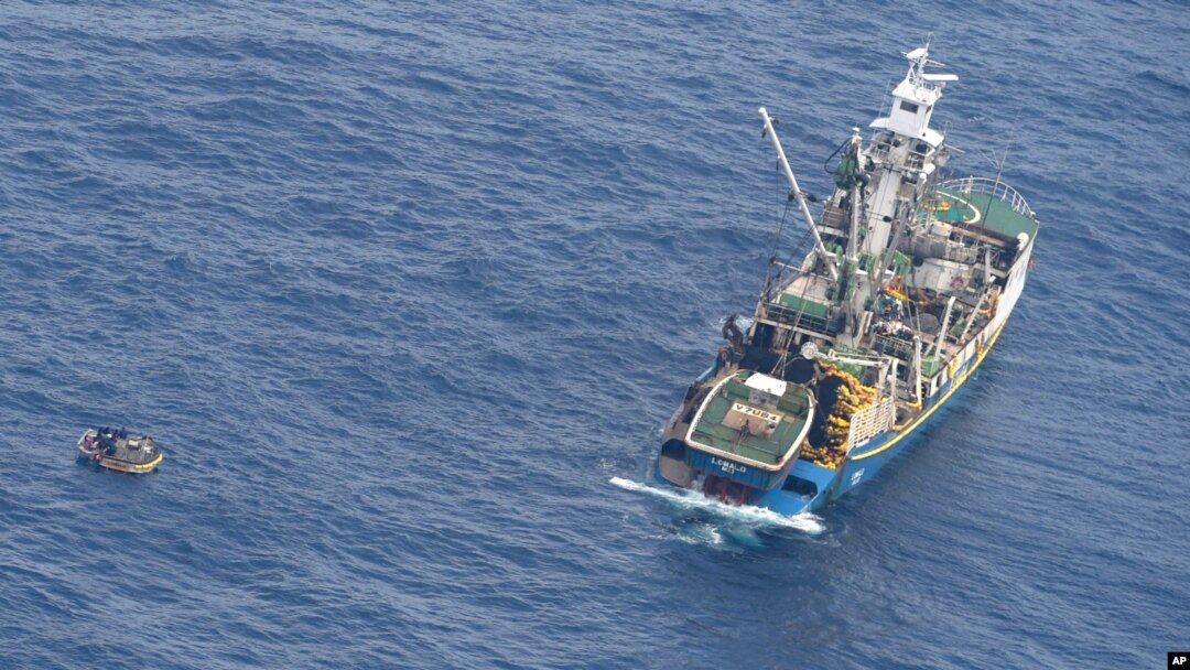 This photo released by the New Zealand Defence Force shows a wooden dinghy, left, carrying seven survivors from a missing ferry and a fishing boat in the Pacific Ocean, Jan. 28, 2018. 