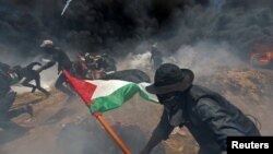 FILE - Palestinian demonstrators run for cover from Israeli fire and tear gas during a protest against U.S. embassy move to Jerusalem and ahead of the 70th anniversary of Nakba, at the Israel-Gaza border in the southern Gaza Strip, May 14, 2018. 