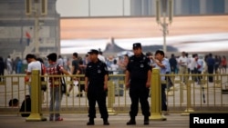 Policemen stand on the road at Tiananmen Square on a hazy day in Beijing on the 24th anniversary of a military crackdown on a pro-democracy movement, June 4, 2013.
