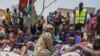 FILE - South Sudanese who fled from Sudan sit outside a nutrition clinic at a transit center in Renk, South Sudan, on May 16, 2023.