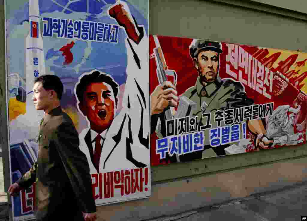 2013年3月26日，一位男士在平壤走过威胁要惩罚“美帝国主义者及其同伙”的宣传画。