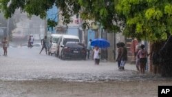 Gente camina por una calle inundada por las lluvias de la tormenta tropical Franklin en Santo Domingo, República Dominicana, el martes 22 de agosto de 2023.