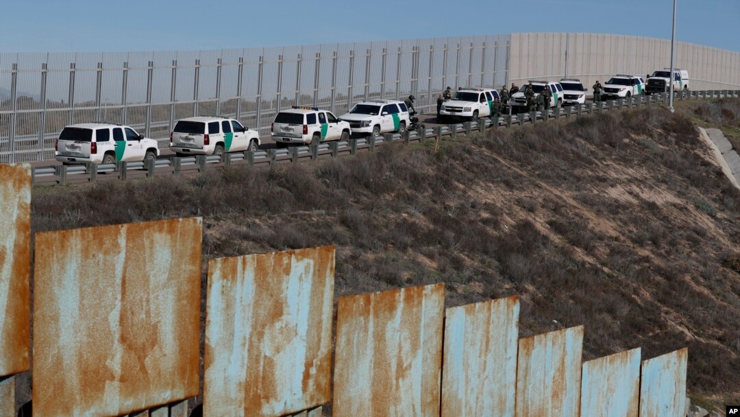 FILE - U.S. Border Patrol vehicles are parked along a secondary fence as they respond to a group of Central American migrants crossing the border wall illegally, seen from across the wall in Tijuana, Mexico, Dec. 9, 2018.