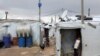 FILE - A Syrian refugee boy stands in front of a tent at an informal tented settlement in the Bekaa valley, Lebanon, March 12, 2021. 