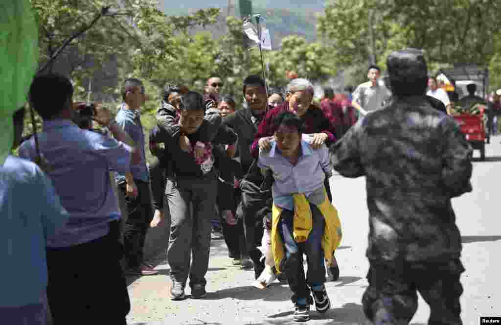 Men carry injured people to an ambulance at Longmen Village, Lushan county, Ya'an, Sichuan province, Apr. 20, 2013.
