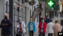 People wearing face masks to protect against coronavirus walk during their allocated time slots for age groups and activities in Madrid, Spain, May 13, 2020.