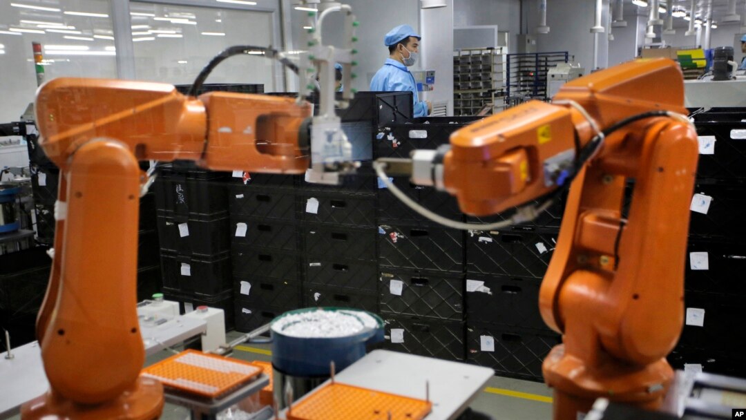 FILe - A Chinese worker is seen behind orange robot arms at work at Rapoo Technology factory in southern Chinese industrial boomtown of Shenzhen, Aug. 21, 2015.