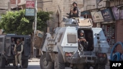 A picture taken on July 26, 2018 shows Egyptian policemen stand guarding a street in the North Sinai provincial capital of El-Arish. Reports say militants attacked a police checkpoint outside the town, June 5, 2019.