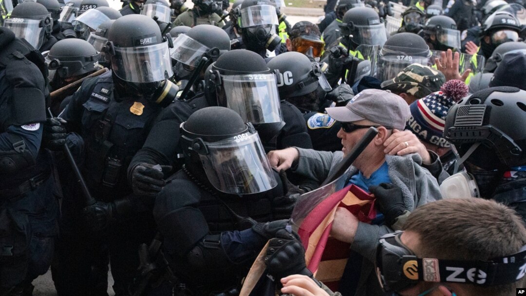 Policías del Capitolio con equipo antidisturbios confrontan a manifestantes que tratan de abrir por la fuerza una puerta del Capitolio de EE.UU. Enero 6, 2021.