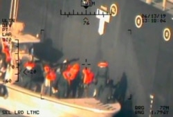 This image released by the Pentagon June 17, 2019, and taken from a U.S. Navy helicopter, shows what the Navy says are members of the Islamic Revolutionary Guard Corps Navy removing an unexploded limpet mine from the M/T Kokuka Courageous.