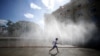 FILE - A child runs under water sprinklers during a heat wave in Vienna, Austria, July 23, 2019. 