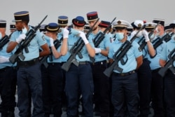 A member of the French military dons her protective face mask during a marching formation practice for the July 14 Bastille Day Parade, Paris, July 12, 2020.