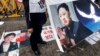 Protester holds sign showing portrait of North Korean leader Kim Jong Un as a portrait of South Korean President Park Geun-hye (L) is seen on the ground, April 11, 2013.