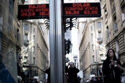 A woman walks under a sign showing exchange rates between the U.S. dollar and Argentine peso in Buenos Aires, Argentina, Sept. 2, 2019.