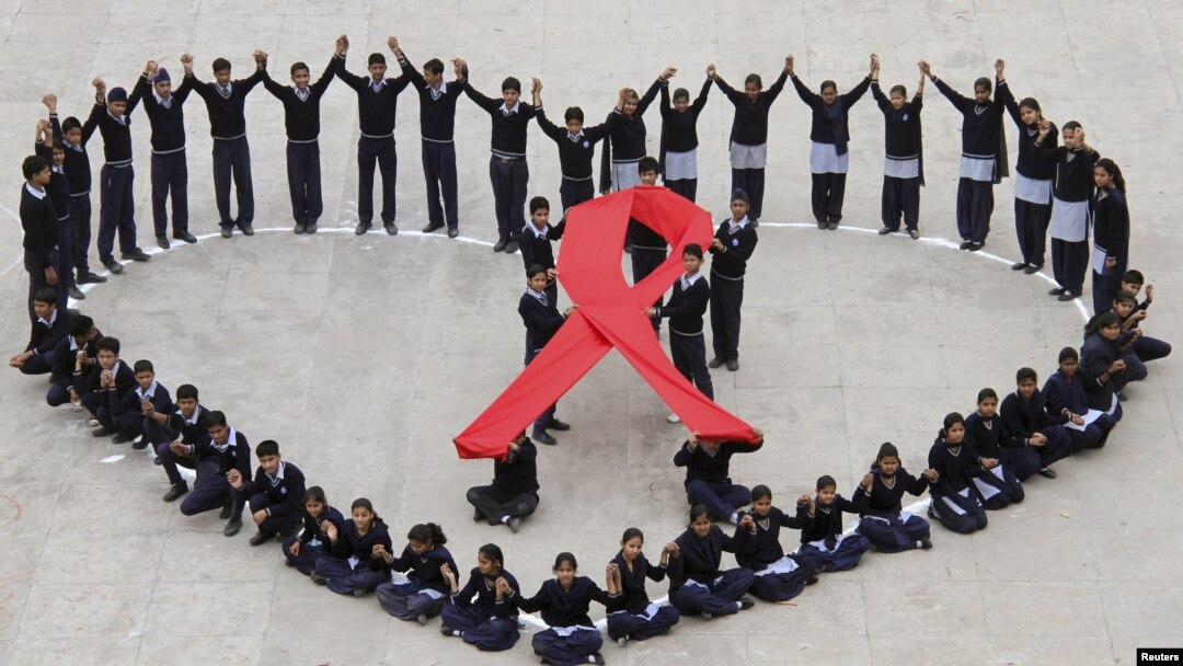 Students make a formation in the shape of a heart and a red ribbon during a HIV/AIDS awareness campaign.