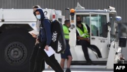Tennis players and officials disembark from a flight after arriving in Melbourne on January 14, 2021, to quarantine ahead of the Australian Open tennis tournament. (Photo by William WEST / AFP)