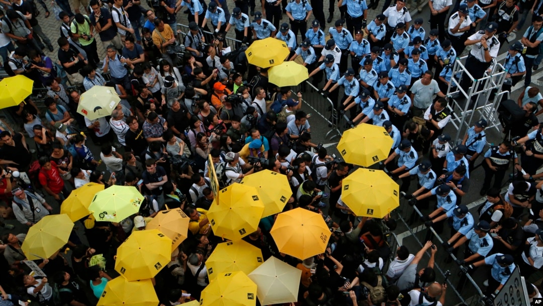 Protesters holding yellow umbrellas gather to observe a moment of silence to mark the first anniversary of "Umbrella Movement" outside the government headquarters in Hong Kong, Sept. 28, 2015. 