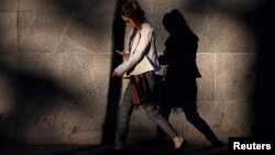 FILE - A young woman looks at her mobile phone early morning in Westminster, London, Britain, Oct. 10, 2016. The suicide rate among British teenagers has nearly doubled, and critics say social media giants are abetting them.