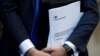 FILE - Conservative Party politician Steve Baker holds a Brexit document as British Member of Parliament, Jacob Rees-Mogg, speaks from St Stephen's Entrance at the Houses of Parliament, in London, Nov. 15, 2018. 